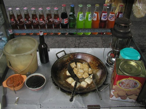 Blick in ein mobiles Warung - in der Pfanne wird Tofu gebraten