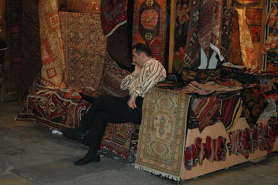 Teppiche (gekn&uuml;pft) und Kelims (T&uuml;rkCe kelimler und gewebt). Der H&auml;ndler wirkt etwas gelangweilt. 